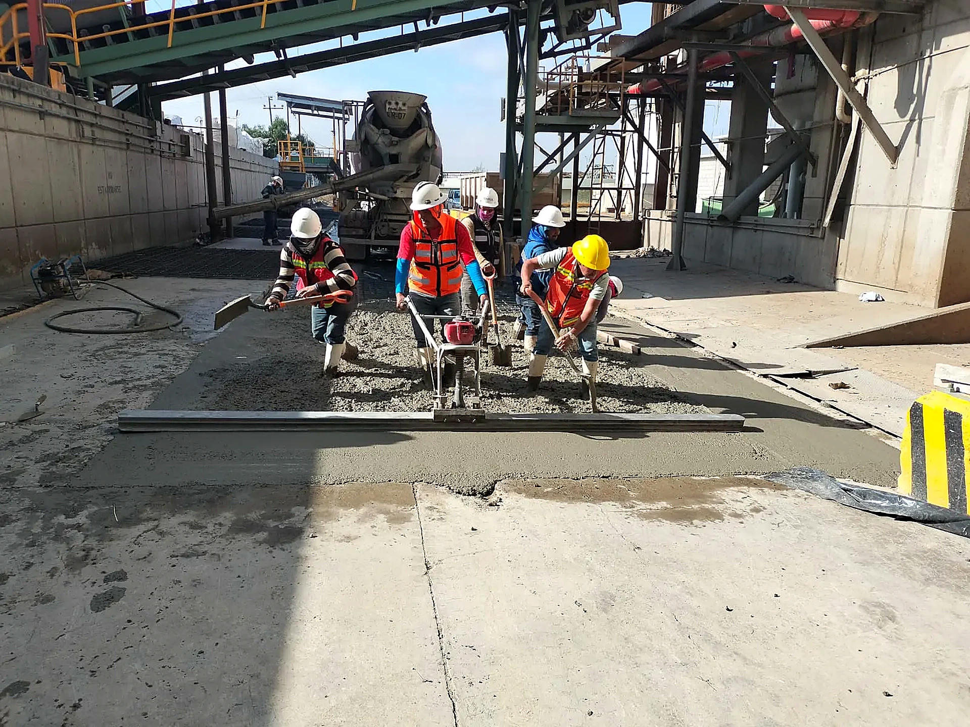 Cuadrilla ejecutando obra de concreto en entorno industrial